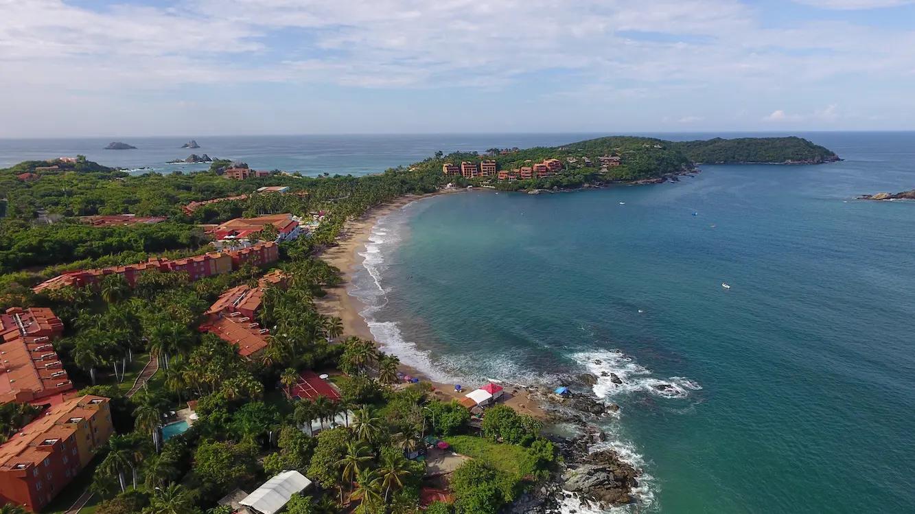 Vista aérea de la impresionante playa de Ixtapa Zihuatanejo bañada por el sol, con aguas turquesas y arena dorada.